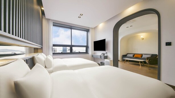 A modern hotel room with a large window, a flat-screen TV, a sofa, and a mirror. - Urban (Mokpo)