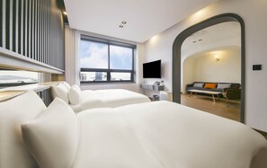 Ett modernt hotellrum med ett stort fönster, en platt-TV, en soffa och en spegel.