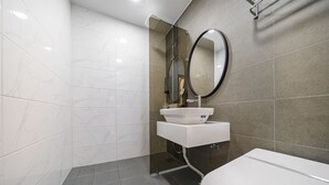 A modern bathroom with a white sink, a round mirror, and a toilet. - Urban (Mokpo)