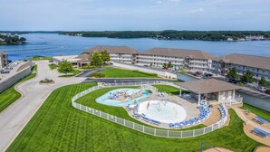 A hotel with a swimming pool, a parking lot, and a view of a lake. - Truly the Best Location & Sunsets on the Lake! Dining & Shopping 2 minutes away! (Osage Beach)