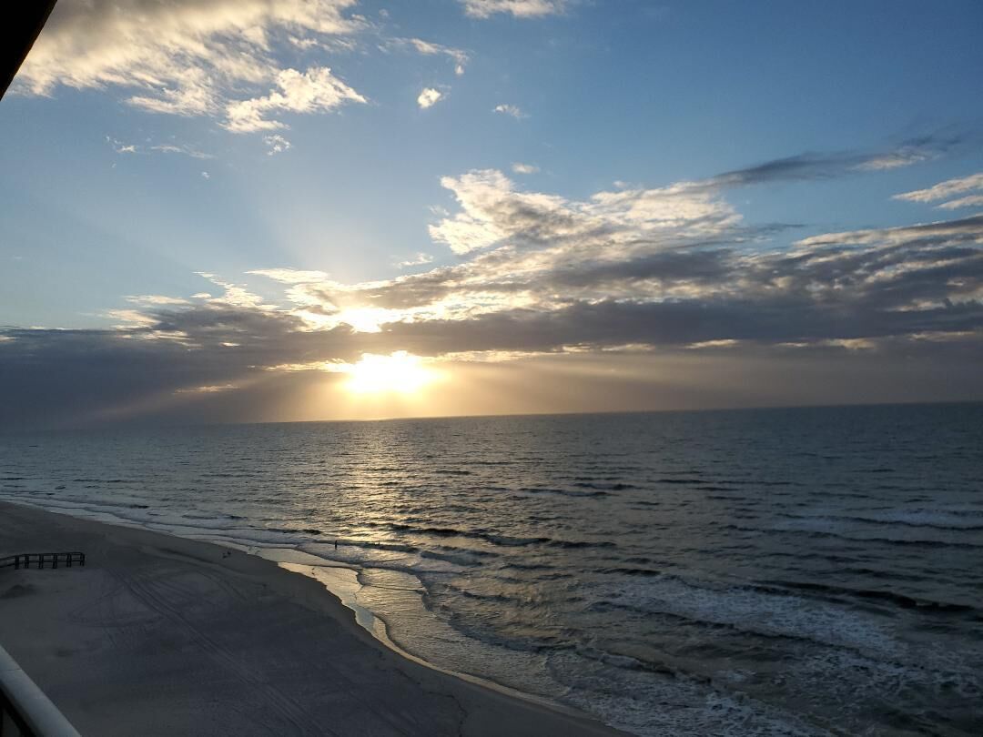 Ein Strand mit Sonnenuntergang über dem Meer, der eine friedliche Atmosphäre schafft.