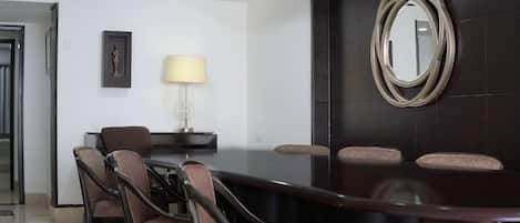 Un salón de conferencias con una mesa de madera oscura, seis sillas, una lámpara y un cuadro en la pared.