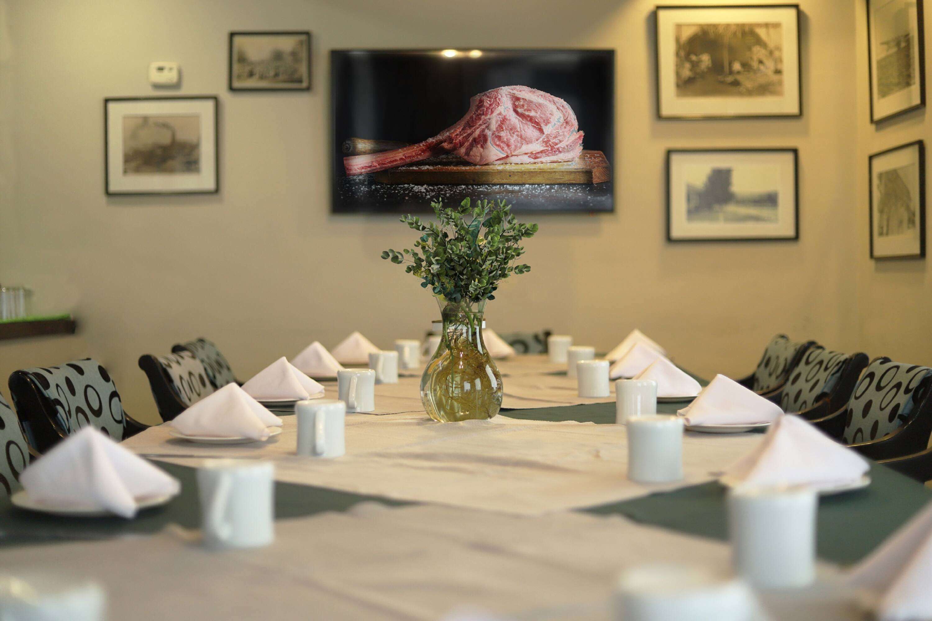 Una mesa de comedor preparada para una comida, con un florero central, rodeada de sillas con tapicería estampada.