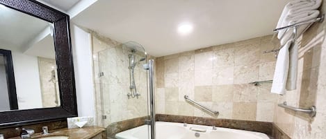 Un baño con una bañera grande, ducha, tocador con lavabo y un perchero para toallas.