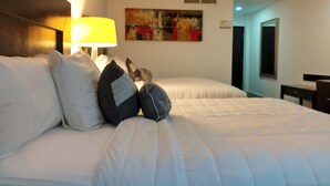 A hotel room with two beds, a bedside lamp, a painting on the wall, and a door leading to another room. - Wyndham Garden Los Mochis Plaza Inn (Los Mochis)