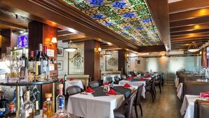 A restaurant with multiple tables, a bar area with bottles, and a stained glass ceiling. - Wyndham Garden Los Mochis Plaza Inn (Los Mochis)