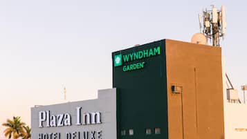 El exterior del Hotel Plaza Inn Deluxe con un letrero Wyndham Garden en la parte superior.