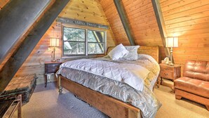 A cozy bedroom with a wooden ceiling, a bed with a patterned bedspread, a leather chair, and a nightstand with a lamp. - Irwin A-Frame Cabin w/ Deck & Mountain Views! (Irwin)
