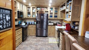 A kitchen with wooden cabinets, stainless steel appliances, and a chalkboard with animal paw prints.