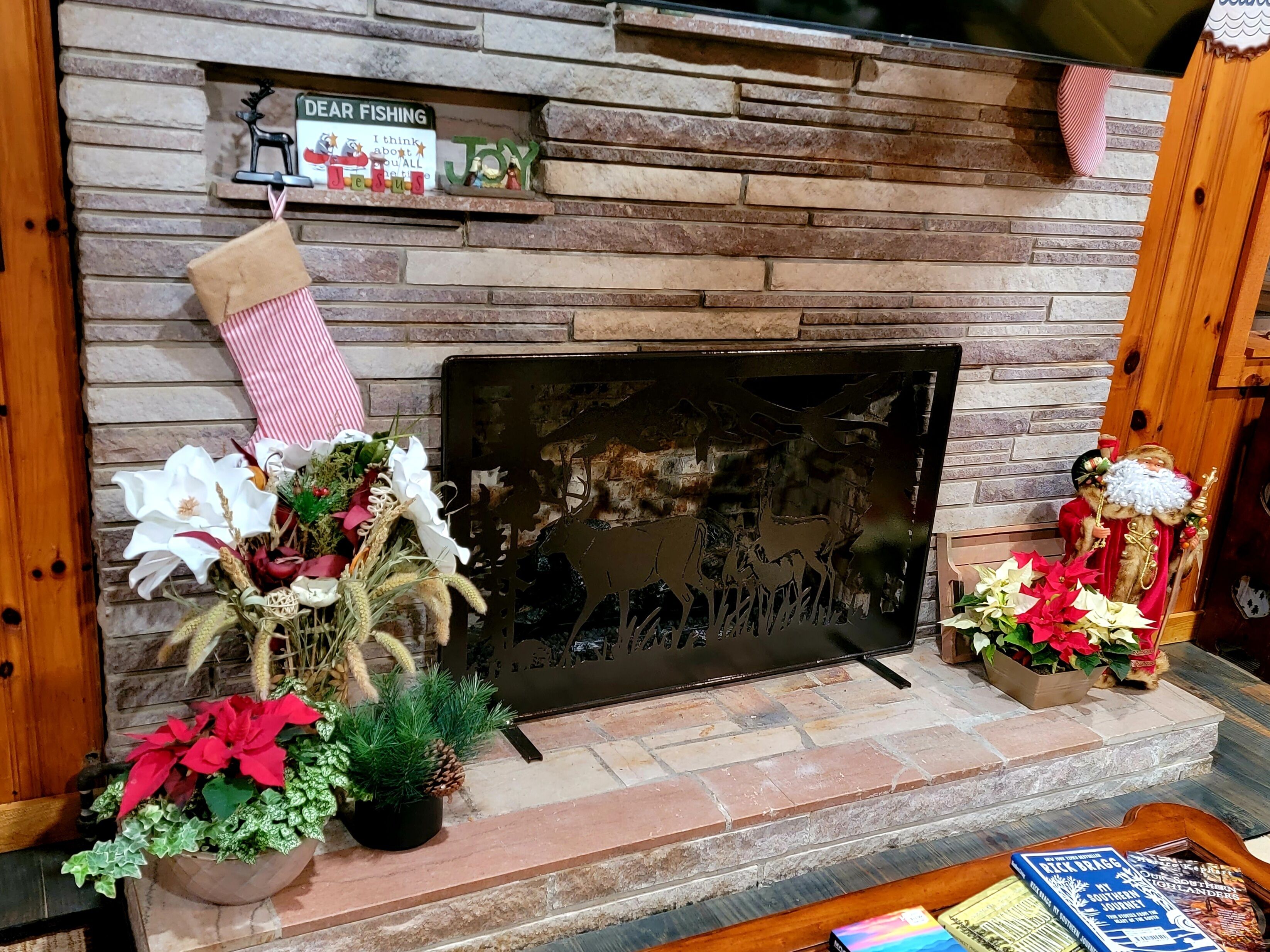 A fireplace with a stone wall, a Christmas stocking, and decorative items including a Santa figurine and poinsettias.