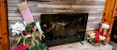 A fireplace with a stone wall, a Christmas stocking, and decorative items including a Santa figurine and poinsettias.