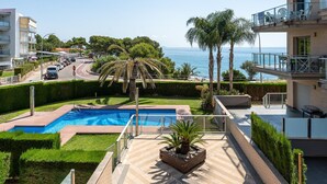 A rooftop pool with a view of the sea, surrounded by palm trees and a well-maintained garden. - Dream vacations sea front with the family (Miami Platja)