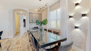 A modern dining area with a glass table, leather chairs, and a large plant. - Rock 'n' Roll Villa with Splash Pad at Encore (Kissimmee)