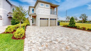 A modern two-story house with a garage, a balcony, and a well-maintained garden. - Rock 'n' Roll Villa with Splash Pad at Encore (Kissimmee)
