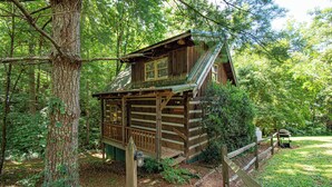 A wooden cabin with a steeply pitched roof, a front porch, and a small deck.