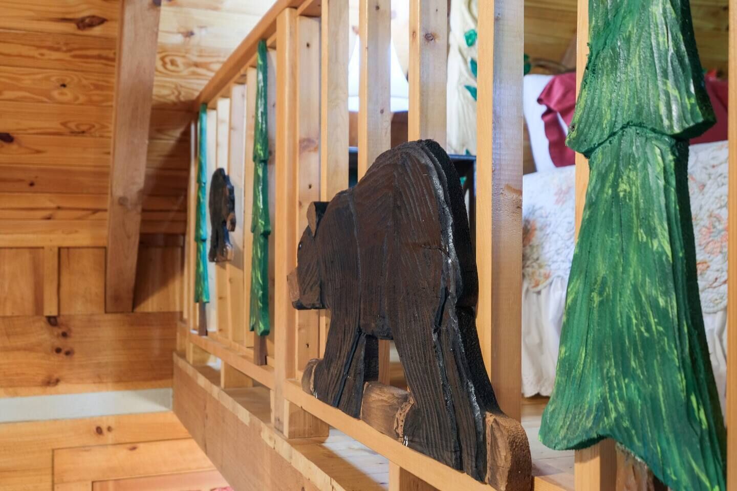 A wooden cabin interior with a wooden bench and a bed with green curtains.