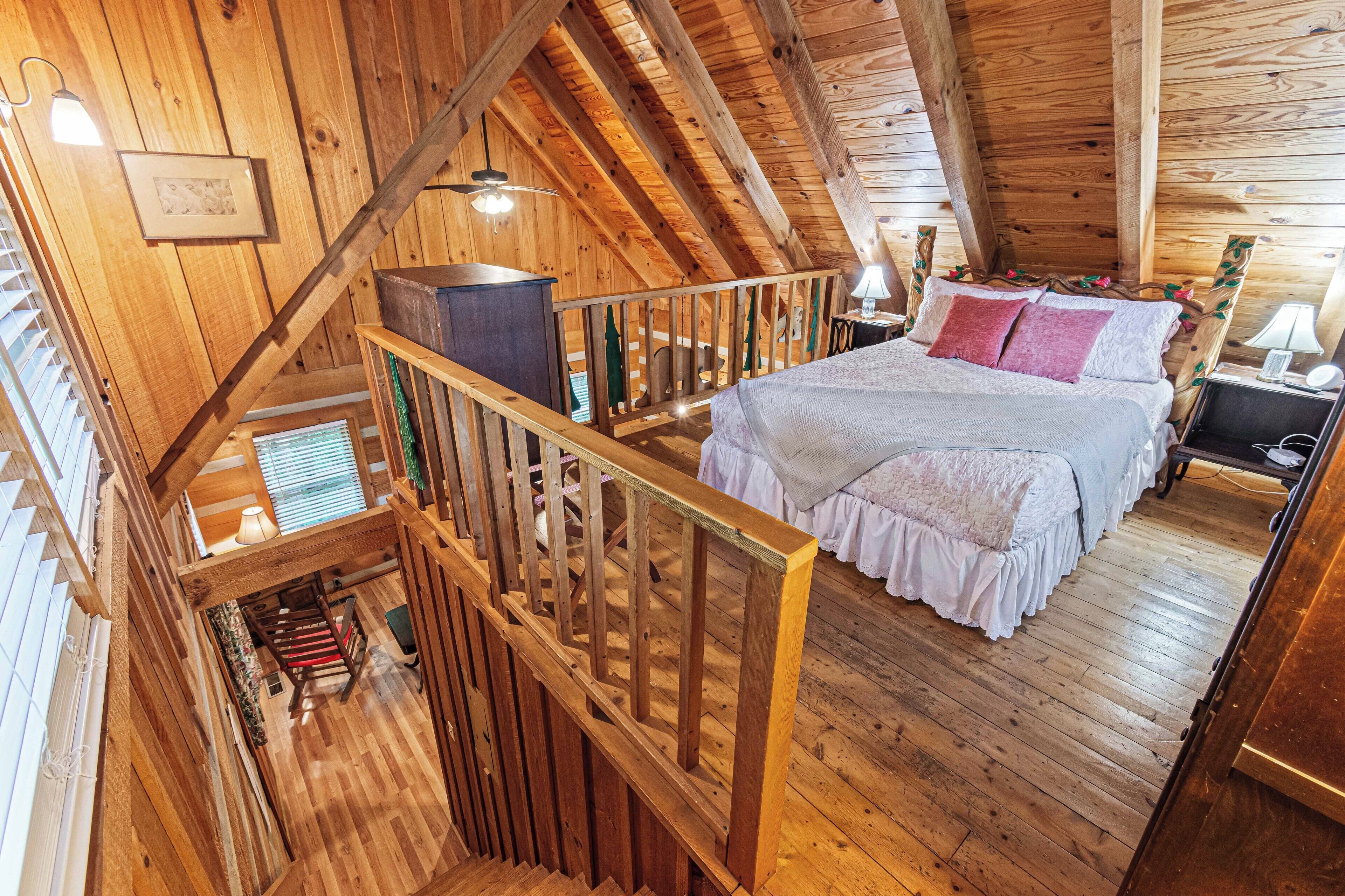 A wooden cabin bedroom with a loft-style bed, wooden beams, and a balcony with a railing.