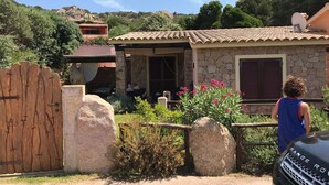 Une maison en pierre avec un toit en tuiles, une porte en bois et un véhicule garé devant.
