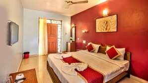 A hotel room with a bed, a ceiling fan, a TV, and a red wall. - Baga Beach Myron (Baga)