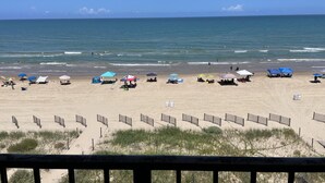 A beach with tents and umbrellas, a sandy area, and a wooden fence. - Beachfront Penthouse, private rooftop balcony & jacuzzi (South Padre Island)