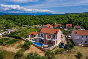 Zona residencial com casas, piscina e montanhas ao fundo.