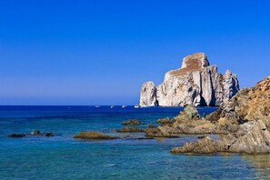 A coastal landscape with rocky formations and clear blue sea.
