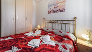 Ein Schlafzimmer mit Bett, Nachttisch, Lampe, einem Bild an der Wand und einem Kleiderschrank.