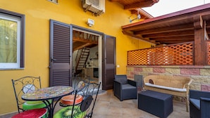 Un patio al aire libre con una mesa, sillas y un sofá de mimbre.