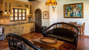 Une cuisine rustique avec des meubles en bois, un coin repas comprenant un canapé et des chaises, et un ventilateur de plafond.