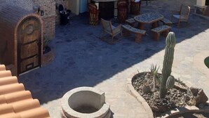 Une cour dotée d’un bar extérieur à toit de chaume, de mobilier en pierre et d’un jardin de cactus.