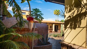 Une cour intérieure agrémentée d’un cactus, de palmiers et d’un bâtiment doté d’un toit en tuiles.