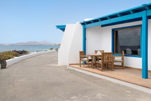 Ein Küstengebäude mit Terrasse, Tisch und Stühlen sowie Blick auf das Meer.