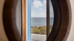 Vista a través de una ventana de madera, con vista a una masa de agua y una zona cubierta de césped.