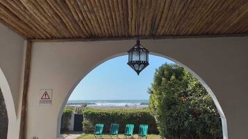 Un espace extérieur aménagé avec des sièges, offrant une vue sur la plage et l’océan.