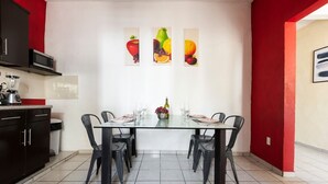 Una cocina moderna con comedor, que presenta una encimera negra, un microondas y una pared de acento roja.