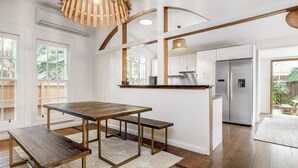 Een moderne keuken met een houten tafel en bank, witte kastjes en een roestvrijstalen koelkast.