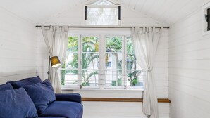 Een kamer met een blauwe bank, een lamp en een raam met gordijnen.