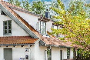 A white building with a sloped roof, a chimney, and a visible door. - Ferienwohnung Mond mit Terrasse, Kamin und Garten - Ferienhaus Sonne, Mond und Sterne bei (Steffenshagen)
