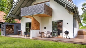 A modern house with a covered patio, outdoor seating, and a barbecue area. - Ferienwohnung Mond mit Terrasse, Kamin und Garten - Ferienhaus Sonne, Mond und Sterne bei (Steffenshagen)