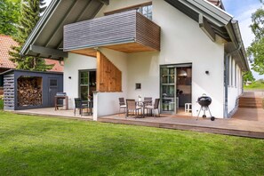 A modern house with a covered patio, outdoor seating, and a barbecue area. - Ferienwohnung Mond mit Terrasse, Kamin und Garten - Ferienhaus Sonne, Mond und Sterne bei (Steffenshagen)