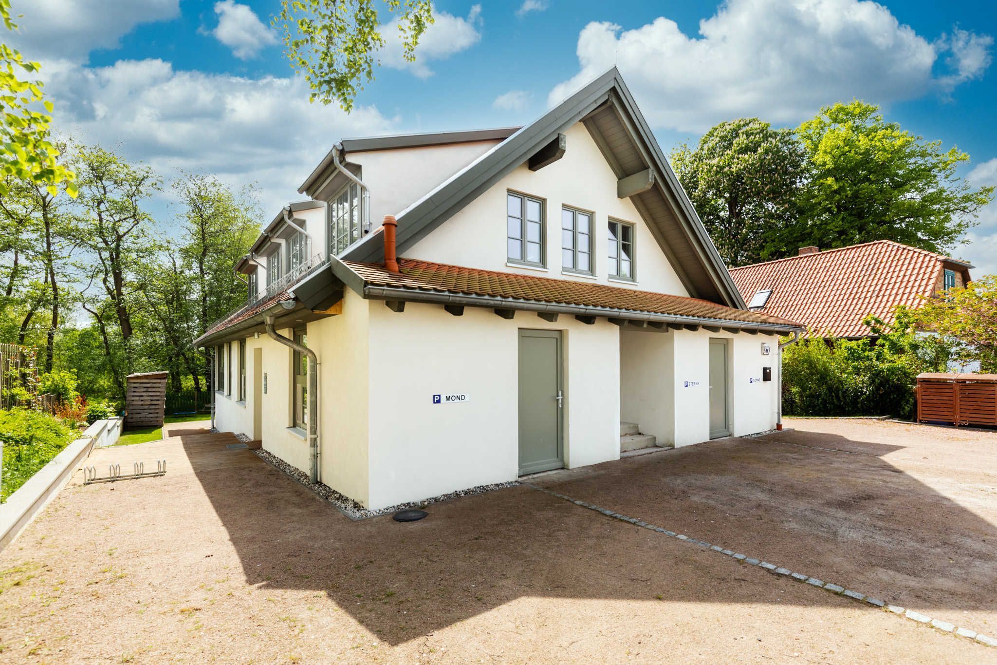 Ein zweistöckiges Haus mit Satteldach, Garage und einem kleinen Anbau.