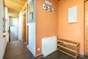 A hallway with wooden flooring, a white radiator, a wooden bench, and a welcome sign. - Ferienwohnung Mond mit Terrasse, Kamin und Garten - Ferienhaus Sonne, Mond und Sterne bei (Steffenshagen)