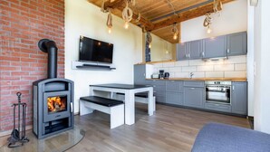A modern kitchen with grey cabinets, a built-in oven, and a TV mounted above the counter. - Ferienwohnung Mond mit Terrasse, Kamin und Garten - Ferienhaus Sonne, Mond und Sterne bei (Steffenshagen)