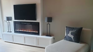 Una sala moderna con chimenea, un televisor de pantalla plana y dos lámparas de pie.