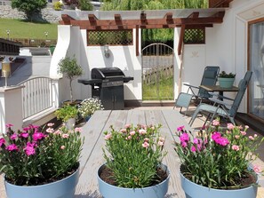 Une terrasse avec un barbecue, des sièges d’extérieur et des plantes en pot.