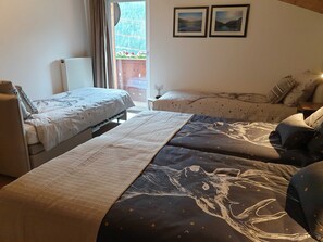 Une chambre avec deux lits, un radiateur, une fenêtre avec des rideaux et deux tableaux encadrés accrochés au mur.