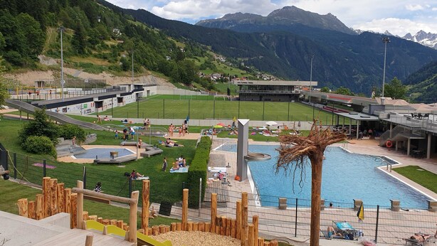 Un resort con piscina, zona de juegos para niños y vistas a la montaña.