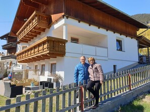 Un bâtiment à deux étages doté d’un balcon, d’une clôture en bois et d’un espace extérieur aménagé pour s’asseoir.