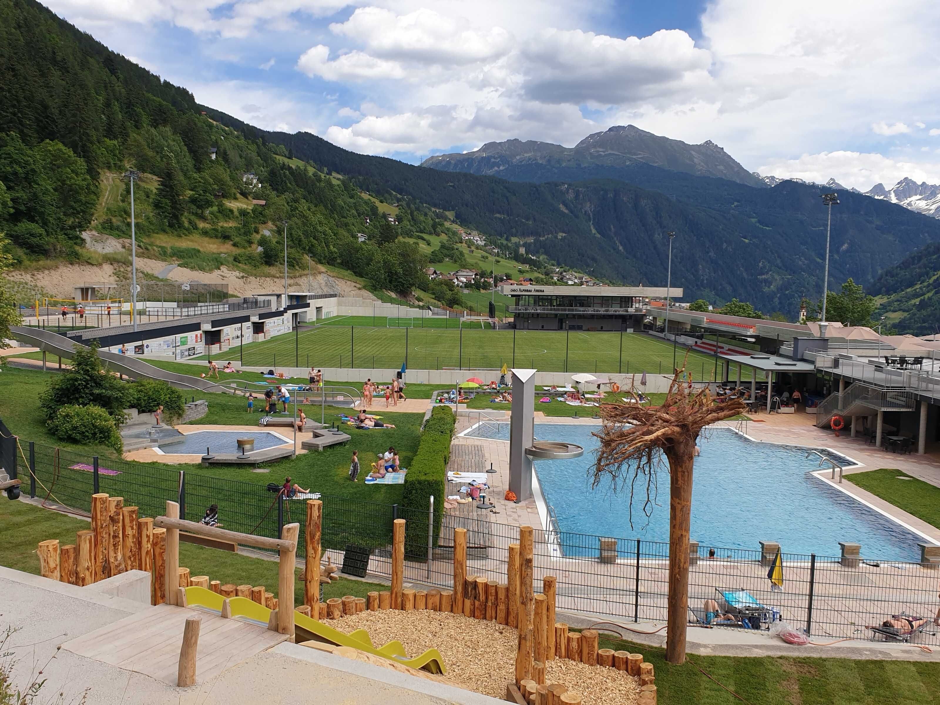Un resort con piscina, zona de juegos para niños y vistas a la montaña.