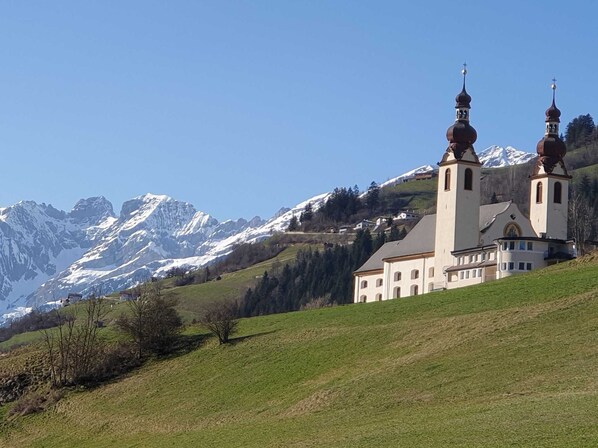A church with two towers and a mountain backdrop.